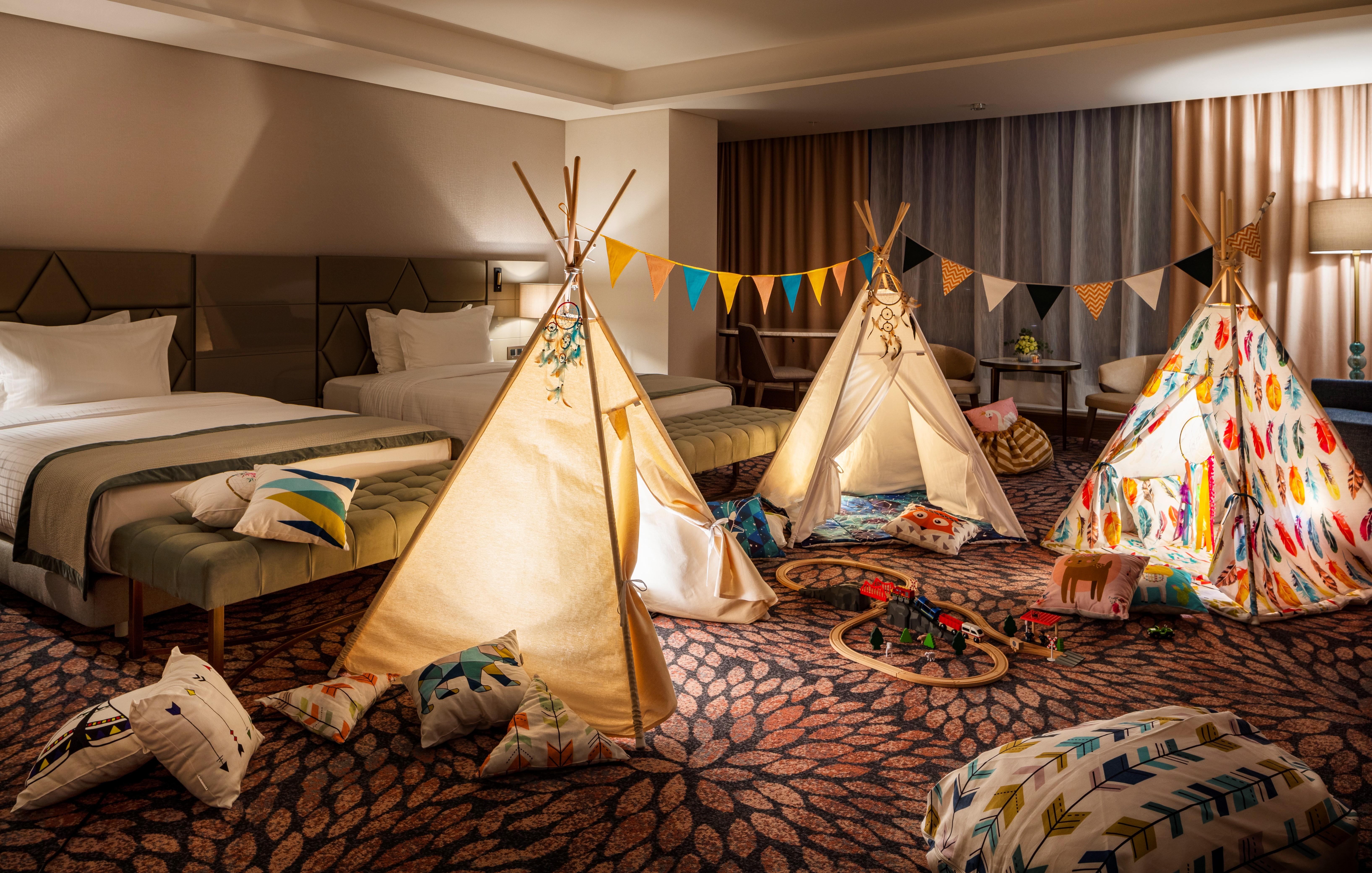 Grand Hotel Millennium صوفيا المظهر الخارجي الصورة The photo shows a cozy room featuring three children's teepees made of fabric, arranged in a playful manner. The teepees are decorated with colorful patterns and surrounded by various cushions and pillows scattered on the floor. There are also decora