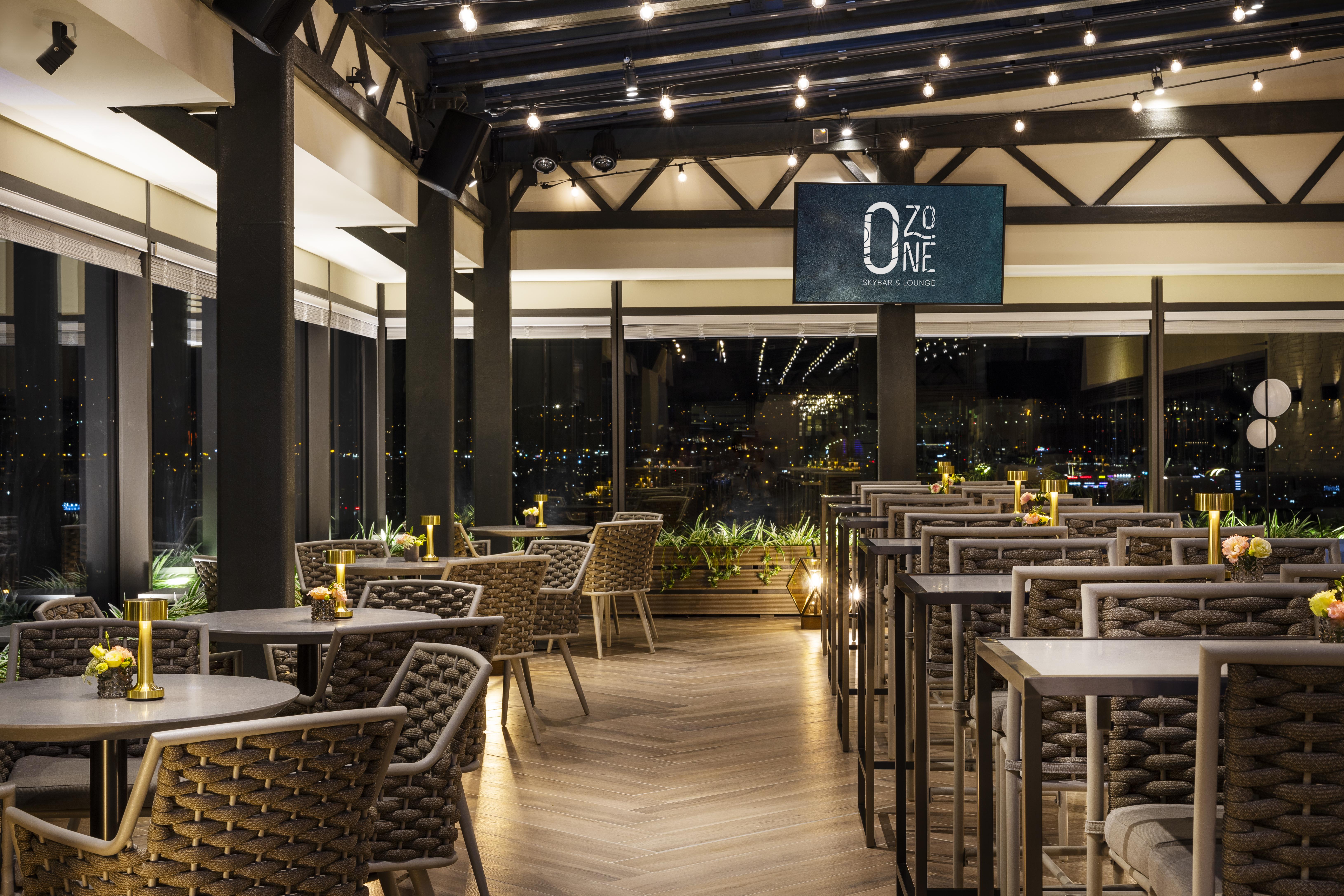 Grand Hotel Millennium صوفيا المظهر الخارجي الصورة The photo depicts a modern restaurant interior with a stylish design. The space features a series of tables and chairs arranged neatly, with a clean and sophisticated aesthetic. The tables are set with small yellow flowers, adding a touch of color to